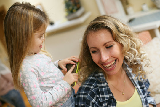 Daughter combing mothers  hair.