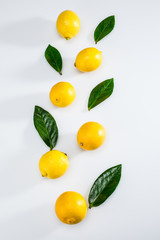 top view of fresh whole lemons and leaves on white