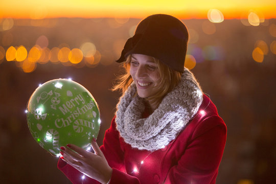 cheerful woman holding a balloon with led lights in winter