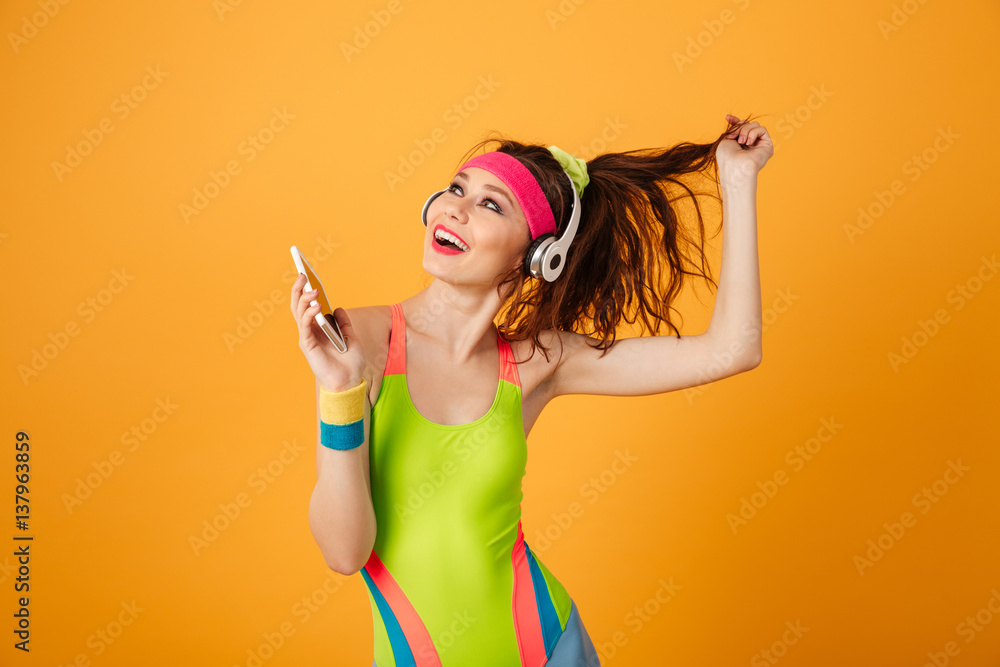 Canvas Prints Cheerful sportswoman listening to music from mobile phone and singing