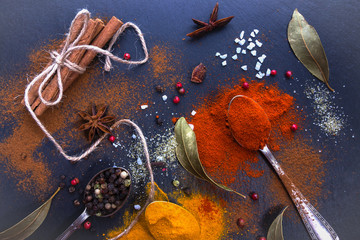 Different spices on a black background. Bay leaf, turmeric, paprika, star anise, cinnamon sticks, pepper. Top view
