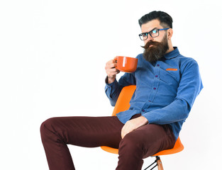 Bearded man, brutal caucasian hipster with moustache holding orange mug