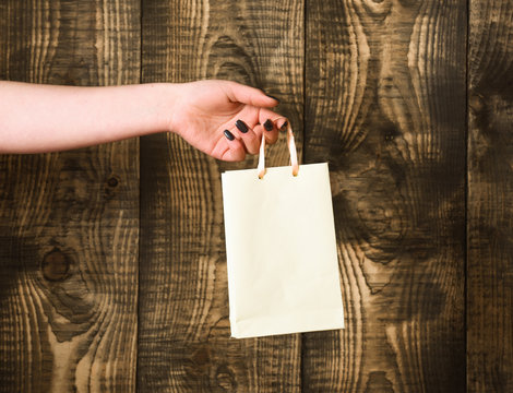 white shopping bag in female hand on wooden background