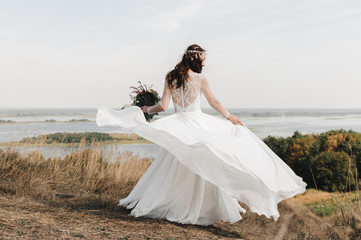 Fototapeta na wymiar Невеста в свадебном платье на горе с видом на просторный разлив реки