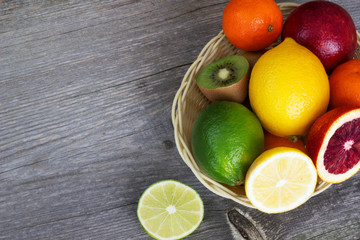 Fototapeta na wymiar Citrus fruit in a basket on a gray wooden background