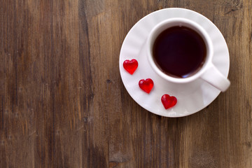 A Cup of tea or coffee with jelly in the shape of heart on wooden background