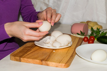 Beautiful female hands peeling a boiled egg from the rind for cooking salad