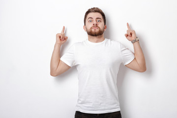 handsome man with beard pointing up. young man looking at camera