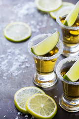 Golden mexican tequila shot with green lime and salt