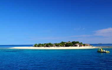 Fototapeta na wymiar Winzige traumhafte Insel im Pazifik / Hütten und Boot / blaues Meer und klarer Himmel / Fiji