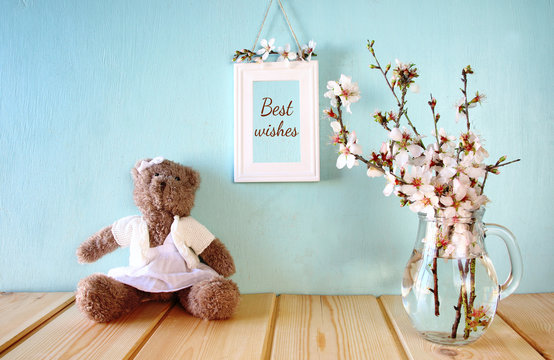 cute teddy bear sitting next to spring cherry tree