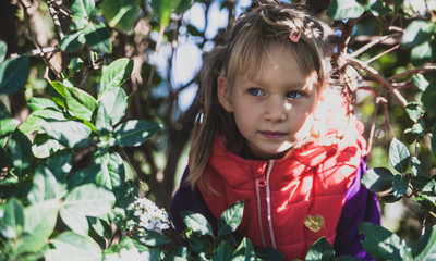 Little pretty girl with blue eyes in a red vest in the park