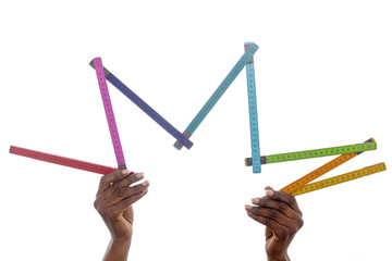 mains femme noire brandissant un mètre en bois coloré