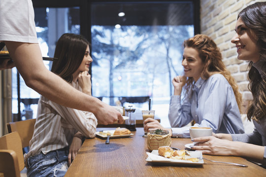 Unrecognisable waiter serving coffee at coffee shop.