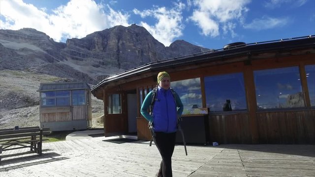 Young female hiker walks walks out of mountain hut restaurant in Dolomite, Italy.