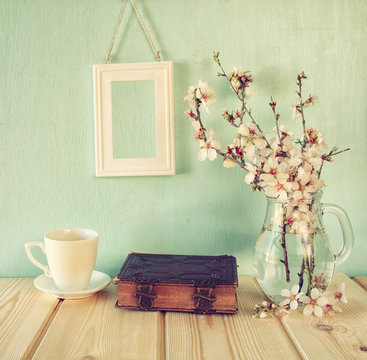 old book, cup of coffee next to spring white flowers