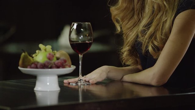 lonely lady touching a glass of red wine in cafe