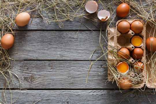 Fresh brown eggs in carton on rustic wood background