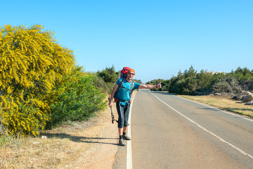 Obraz premium Bearded man with backpack is traveling hitchhiking