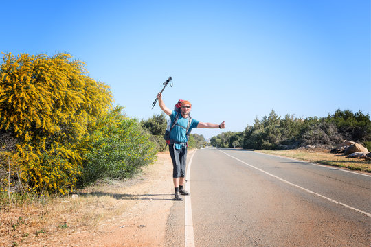 Joyful bearded man with backpack is traveling hitchhiking
