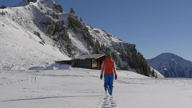 Girl goes to the chalet on the slope of the Alpen mountains