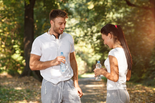 Young Couple Resting And Talking After Running In Park