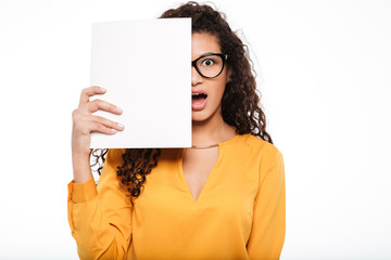 Astonished african businesswoman covered half face with blank paper sheets