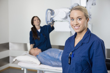 Young Radiologist Smiling While Colleague Taking Patient's Xray