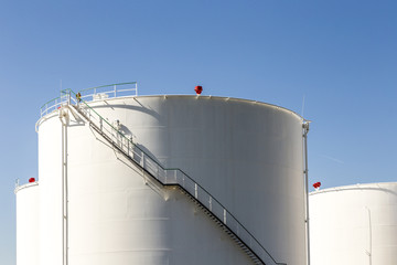 white tanks in tank farm with iron staircase