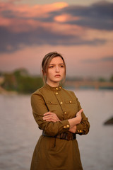 Fototapeta premium Pretty sad girl in Soviet war uniform in sunset