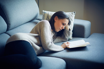 Ragazza legge libro sul divano a casa