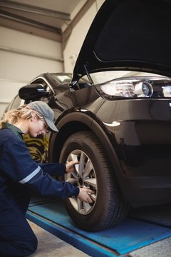 Female mechanic examining a car wheel