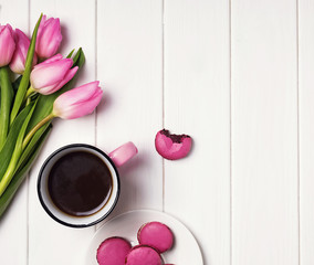 Coffee, pink tulips and macarons on the white wooden table