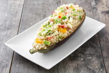 Stuffed eggplant with quinoa and vegetables on wooden background

