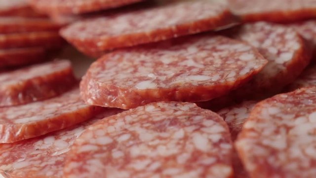 Dry salami pieces on plate food background slow pan 4K 2160p 30fps UltraHD footage - Cured sausage air-dried meat cuts pile 3840X2160 UHD panning video 