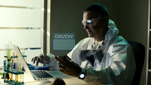 Serious professional male specialist while online shopping in his office. Senior man use credit card and enter secure CVC/CVV code from reverse side of a credit card. He got successful payment and