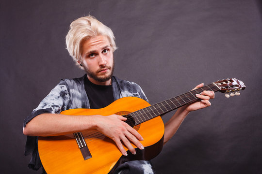 Blonde man playing acoustic guitar