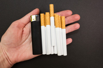 Cigarettes and a lighter in the hand of the woman on a black background
