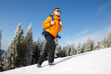 Fototapeta na wymiar Hiker in winter mountains. Man with backpack trekking in mountains. Winter hiking