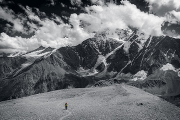 A lone tourist among the big mountains. Black and white photo.