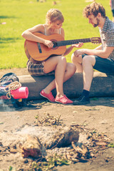 Young couple camping playing guitar outdoor