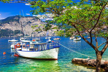 Pictorial scenery with boats in beautiful lake Lago di Garda. Italy - obrazy, fototapety, plakaty
