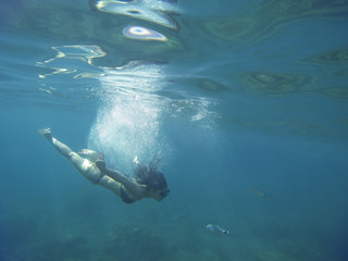 breathtaking turquoise sea with a young woman scuba diving isolated under the sea
