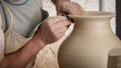 Old craftsman hands working on pottery wheel