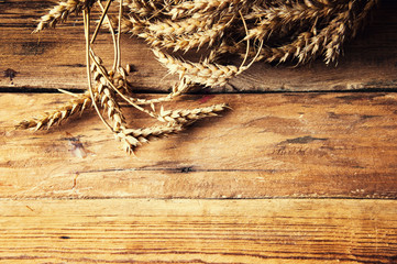 Wheat ears on wooden background, copyspace