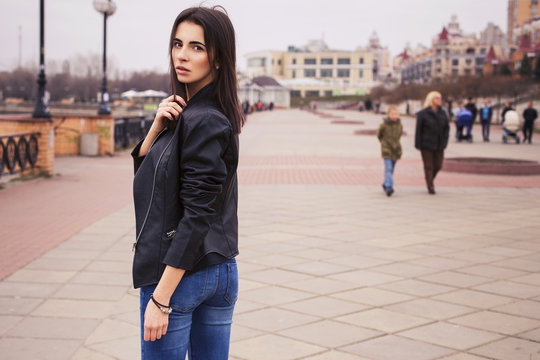 beautiful brunette woman in black leather jacket walking on the european city street - Powered by Adobe
