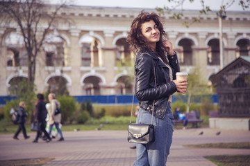 Brunette beautiful stylish caucasian woman in casual outfit on a walk on european city street drinking coffee. copy space