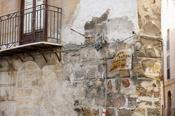 Detail of the corner of an old stone house with wiring and oldness of signboard in Palermo, Italy. Text: "Welding work Electric and gas welding.."
