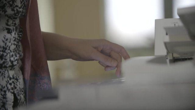 Close up handheld 4k shot of female hands preparing printer to print documents. Enable and Configure menu. Paperwork, working day in the office, business concept.