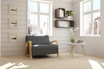 White room with armchair and winter landscape in window. Scandinavian interior design